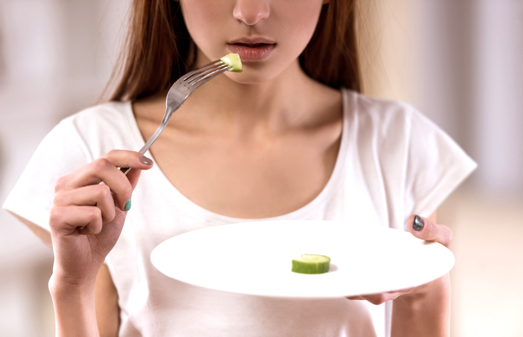 小さくカットされた野菜を食べる女性