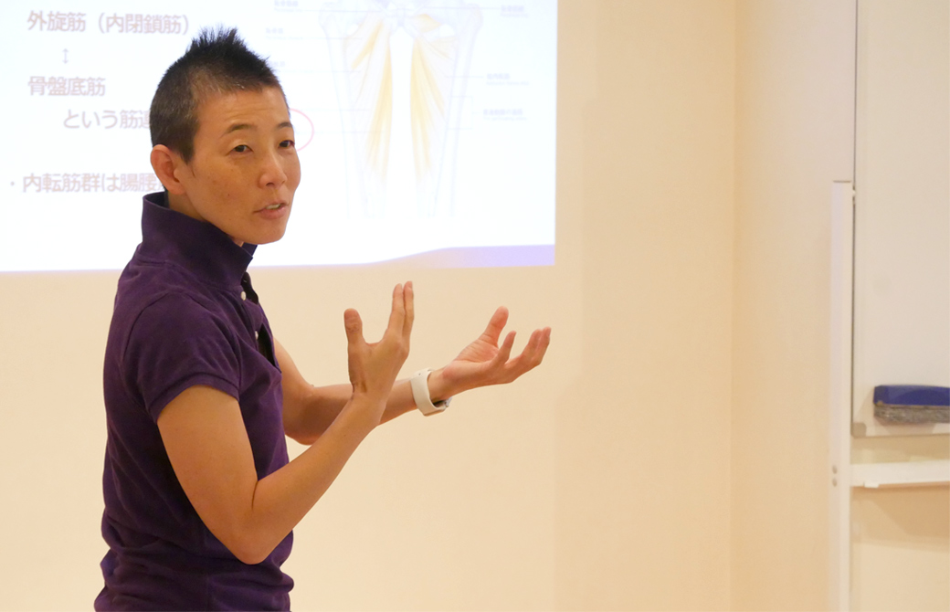 高尾美穂先生がプロジェクターの映像の前で手振りを使いながら説明している様子