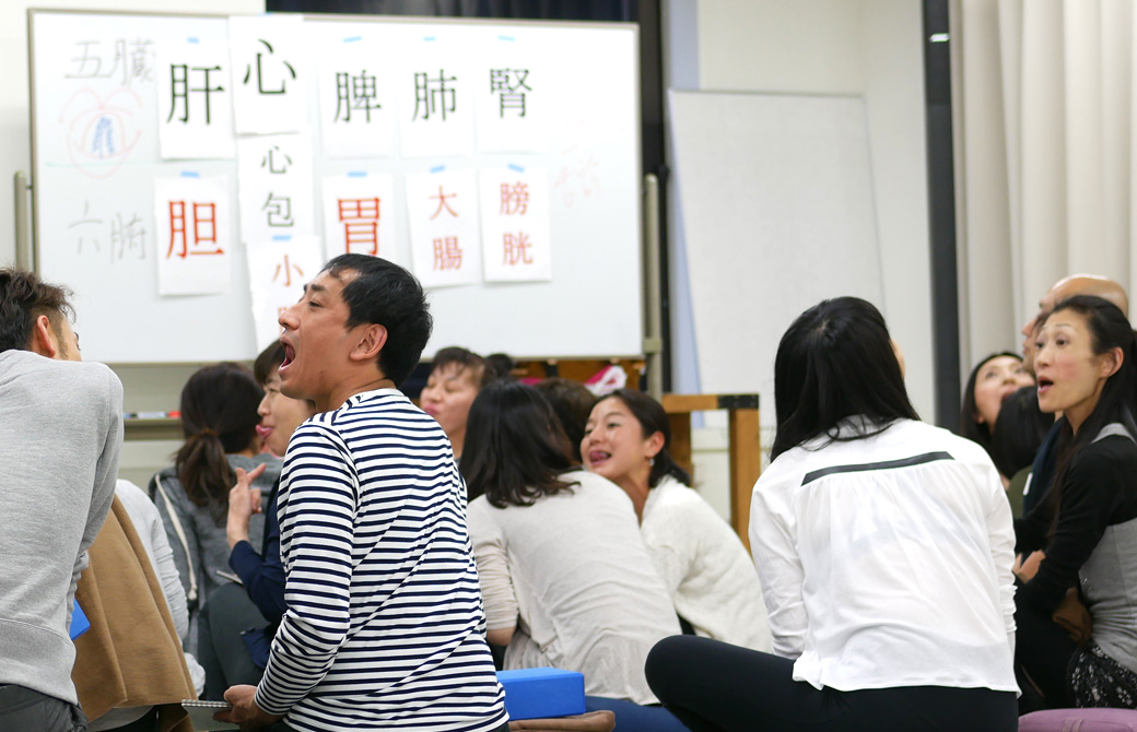 経絡ワークショップの講座風景。大勢の生徒さんがお互いに舌の裏側を見せ合いっこしている様子