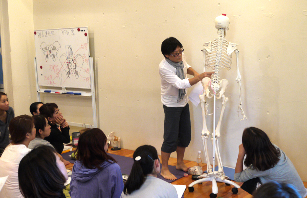 ヨガ解剖学骨盤セラピーの講座風景。講師内田かつのりが全身骨模型で説明している様子