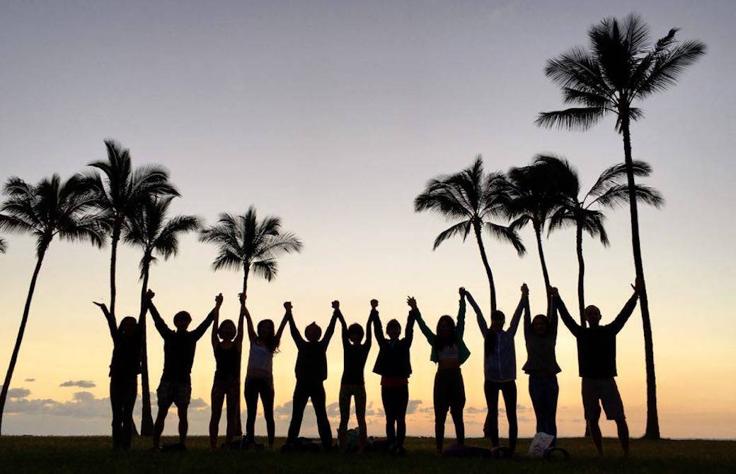 夕日と海を背景にサンガワイ参加者が手をつなぎ万歳