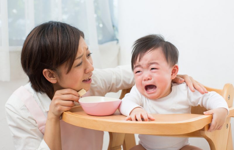 ご飯を食べさせるママと泣く赤ちゃん 