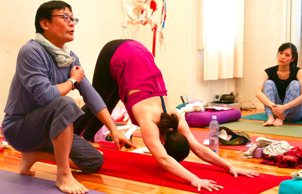 内田先生がダウンドッグをしている生徒さんをモデルに説明している様子