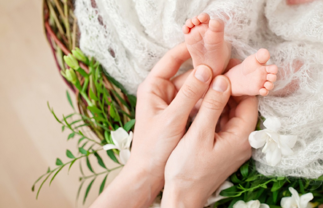 赤ちゃんの足を優しく触るママの手