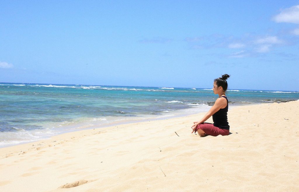 ヨーコ・フジワラ先生がハワイの砂浜で座っている